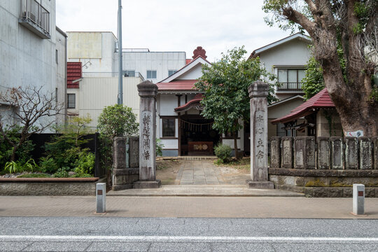 View of an ornate Daishido Temple entrance with stone pillars framing the path, amidst aged buildings under a cloudy sky, Narita, Chiba, Japan.