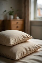 Obraz premium Two pillows stacked on bed in bedroom with natural light and wooden furniture