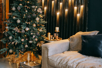 Decorated Christmas tree with golden ornaments and cozy sofa in a festive home interior. Holiday season and winter celebration concept.