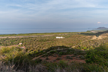 Fototapeta premium A wide, high-angle view of an arid coastal landscape in rural Indonesia. The sea and distant islands are on the horizon. A remote, dry scrubland. 