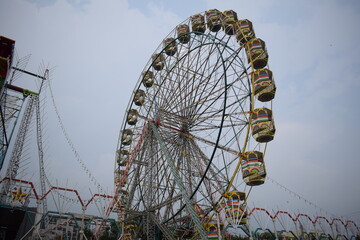 Closeup of multi-coloured Giant Wheel during Dussehra Mela in Delhi, India. Bottom view of Giant Wheel swing. Ferris wheel with colourful cabins during evening time.
