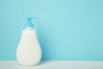 White plastic bottle of liquid soap on blue background.