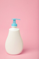 White plastic bottle of liquid soap on pink background. Vertical photo