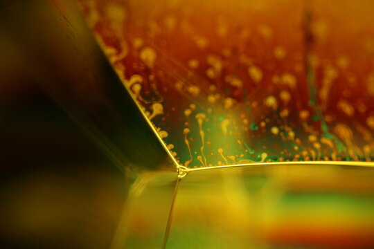 Yellow liquid surface, geometric structure, green oils on a dark background, colourful abstract, surrealistic art, iridescent effect