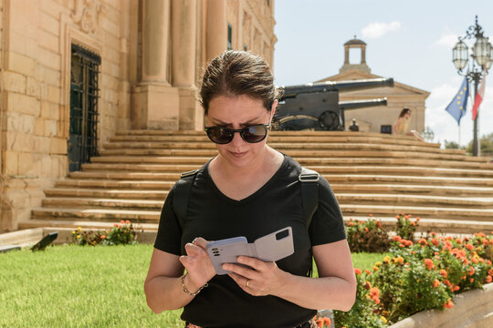Plano cercado de turista mujer en La Valeta, Malta, caminando y escribiendo por tel&eacute;fono m&oacute;vil. 