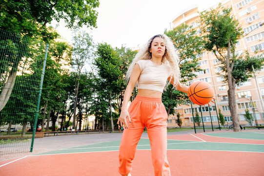 Calm moment on court: woman holding basketball at waist, eyes closed, mindful breathing before game.