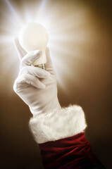 Imagination at Christmas with Santa's hand holding light bulb
