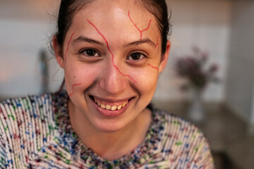 Excited teen showing Halloween sketch makeup with red lines