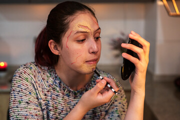 Thoughtful woman blending textures for artistic Halloween makeup