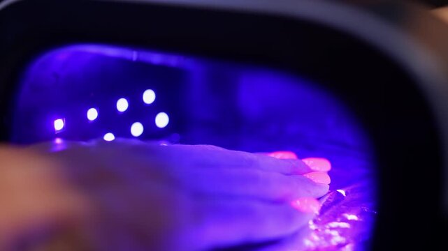 A client puts her hand with painted nails into an LED lamp for polymerization. High quality 4k footage