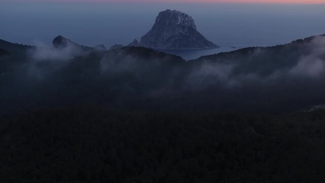 Aerial view of Es Vedra island in Ibiza emerging from fog. Breathtaking, colorful sunrise over the Mediterranean Sea in Balearic Islands