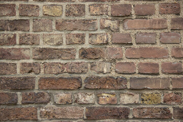 Textured brick wall featuring a mix of earthy tones and varying sizes, showcasing the rustic charm and durability of traditional masonry in an urban environment