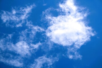 Bright Sun Shining Through Wispy Clouds Against a Deep Blue Sky.
