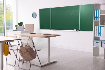 Green chalkboard and stylish furniture in classroom. Mockup for design