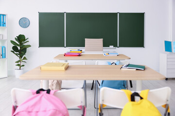 Green chalkboard, desks and chairs in classroom. Mockup for design