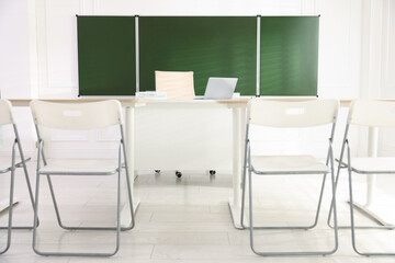 Green chalkboard and stylish furniture in classroom. Mockup for design