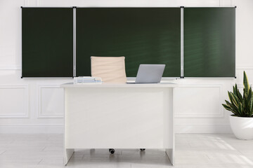 Green chalkboard, chair, houseplant and desk in classroom. Mockup for design