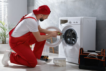 Professional repairman fixing broken washing machine indoors