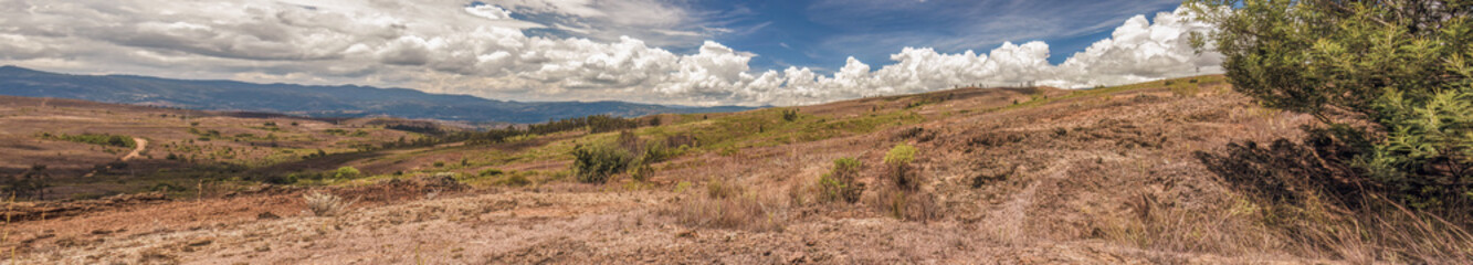 Composite panorama of the landscape of the La Candelaria desert, with dense bright clouds at the horizon, in the eastern Andean mountains of central Colombia, near the town of Raquira.