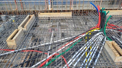 construction site view of rebar mesh and colorful electrical conduits