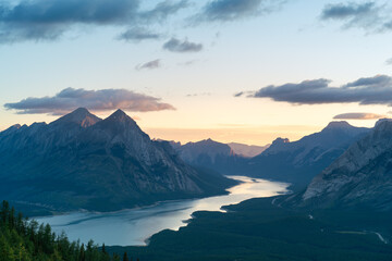 Mountain peaks frame a reflective lake at sunrise, creating a serene vista.