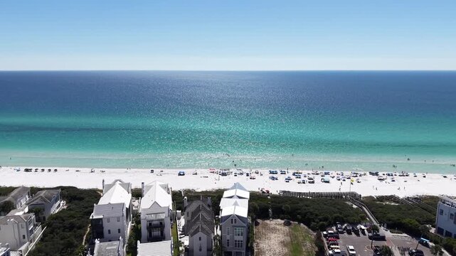 Panoramic drone fly at Gulf of Mexico resort neighborhood with turquoise ocean and white sandy beach in season, 30A, Florida, USA