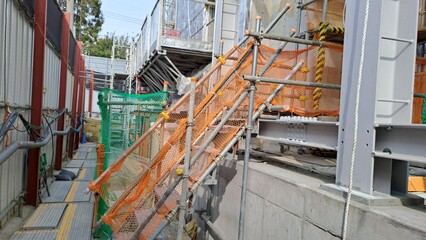 temporary scaffolding stairs with orange safety netting on a building construction site