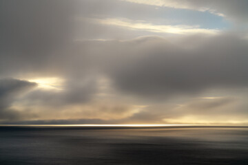long exposure of a tempestuous sky and calm North Atlantic off the coast of the Faroe Islands at sunrise