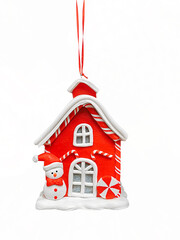 A charming red ceramic Christmas ornament shaped like a candy-cane-roofed house, featuring a snowman. Hanging on a ribbon, perfectly isolated on white for holiday design