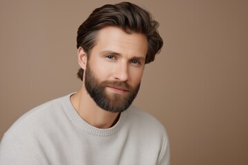 Fototapeta premium Bearded man with confident expression is posing against a neutral background, showcasing a relaxed demeanor and stylish appearance, perfect for lifestyle and portrait photography