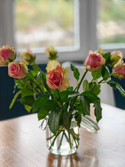 Beautiful roses in a glass jar stand on the table