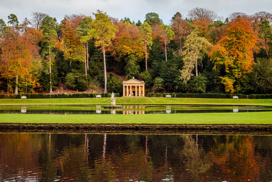 A cropped view of Studley Royal Water Garden in North Yorkshire, with trees and water reflecting warm fall colors under soft seasonal light