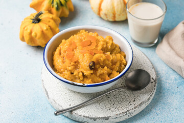 Pumpkin squash porridge with dried apricots and raisins on blue background with pumpkins