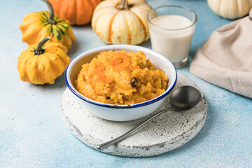 Pumpkin squash porridge with dried apricots and raisins on blue background with pumpkins