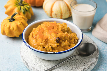 Pumpkin squash porridge with dried apricots and raisins on blue background with pumpkins
