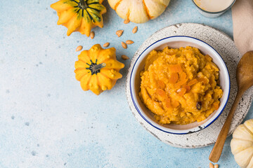 Pumpkin squash porridge with dried apricots and raisins on blue background with pumpkins