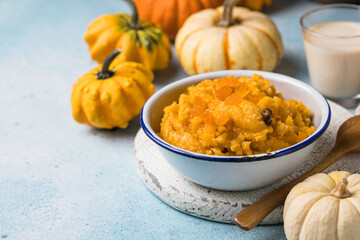 Pumpkin squash porridge with dried apricots and raisins on blue background with pumpkins