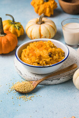Pumpkin squash porridge with dried apricots and raisins on blue background with pumpkins