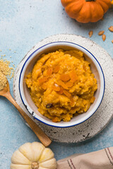 Pumpkin squash porridge with dried apricots and raisins on blue background with pumpkins