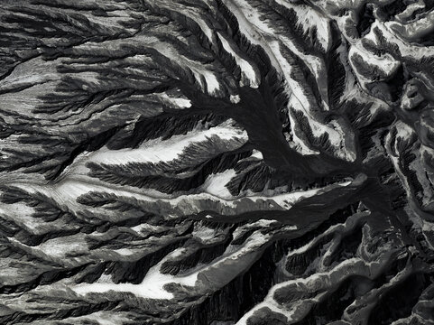 Aerial view of stark, branching patterns etched into the landscape, contrasting light and shadow, creating an abstract monochrome tapestry, Mount Bromo, East Java, Indonesia.