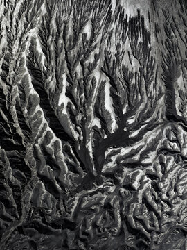 Aerial view of stark, branching patterns etched into the volcanic landscape, creating a mesmerizing contrast of light and shadow, Mount Bromo, East Java, Indonesia.