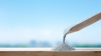 Obraz premium Concrete mixture pouring on wooden surface with clear blue sky background, symbolizing construction work and building process