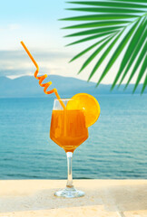 fruit cocktail with straw on sunny beach, fruit drink with orange slice against backdrop blue sea, tropical Vacation and relaxation, Travel and destination, and healthy lifestyle, holiday Paradise
