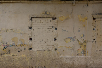 Texture of a brick wall with old, peeling paint in some partially ruined buildings