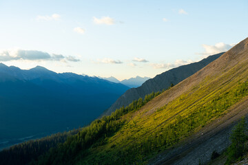 A mountain range view with sunlit peaks and valleys under a blue sky.