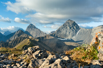 Fototapeta premium Majestic mountain peaks piercing the sky under a partly cloudy afternoon.