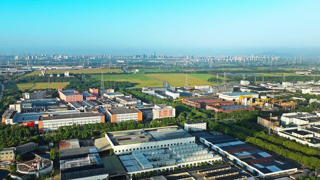 Aerial shot of a large industrial park with factory buildings and a modern city skyline in the background 