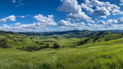 Naklejka premium Vast landscape of green hills under bright blue sky, with distant mountains. Clouds dot sky, casting soft shadows on hills, creating serene scene. Neural network AI generated