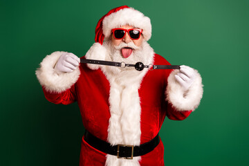 Fun Santa in red suit wears hat and white fur trim with belt and sunglasses posing against green...