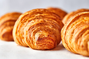 Croissant closeup. Macro photo of croissants on white textile with selective focus. Puff pastry image for advertising, magazine, bakery. Traditional delicious French pastry concept